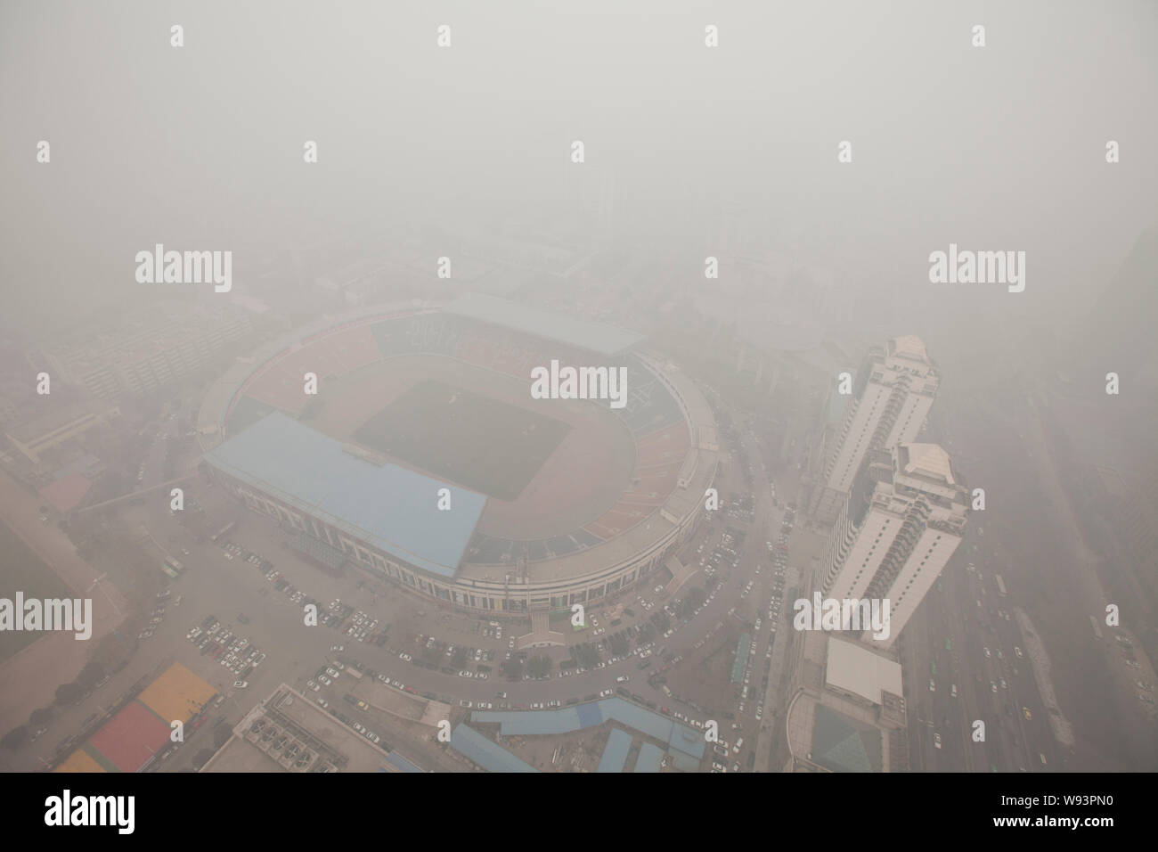 A stadium and residential apartment buildings are seen vaguely in heavy smog in XiAn city, northwest Chinas Shaanxi province, 24 December 2013.   Heav Stock Photo