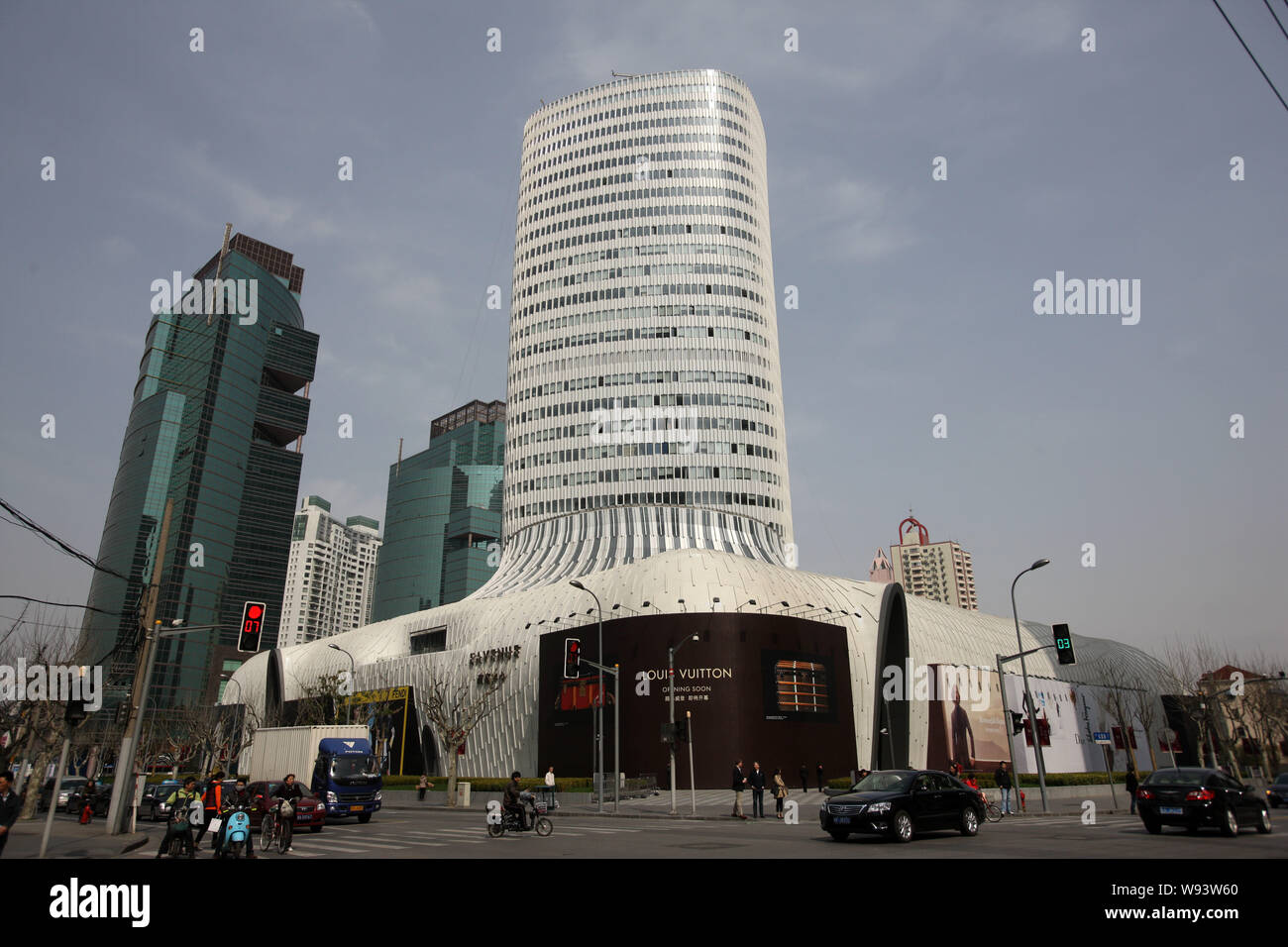 Cyclists and cars drive past the LAVENU Center, also known as Boot Tower, at Hongqiao in Shanghai, China, 14 March 2013.   The LAVENU Center under LVM Stock Photo