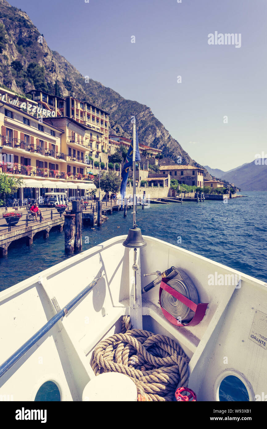 Bow of a boat on a boat tour. Blue water, moutnain range and little village, Lago di Garda, Italy Stock Photo