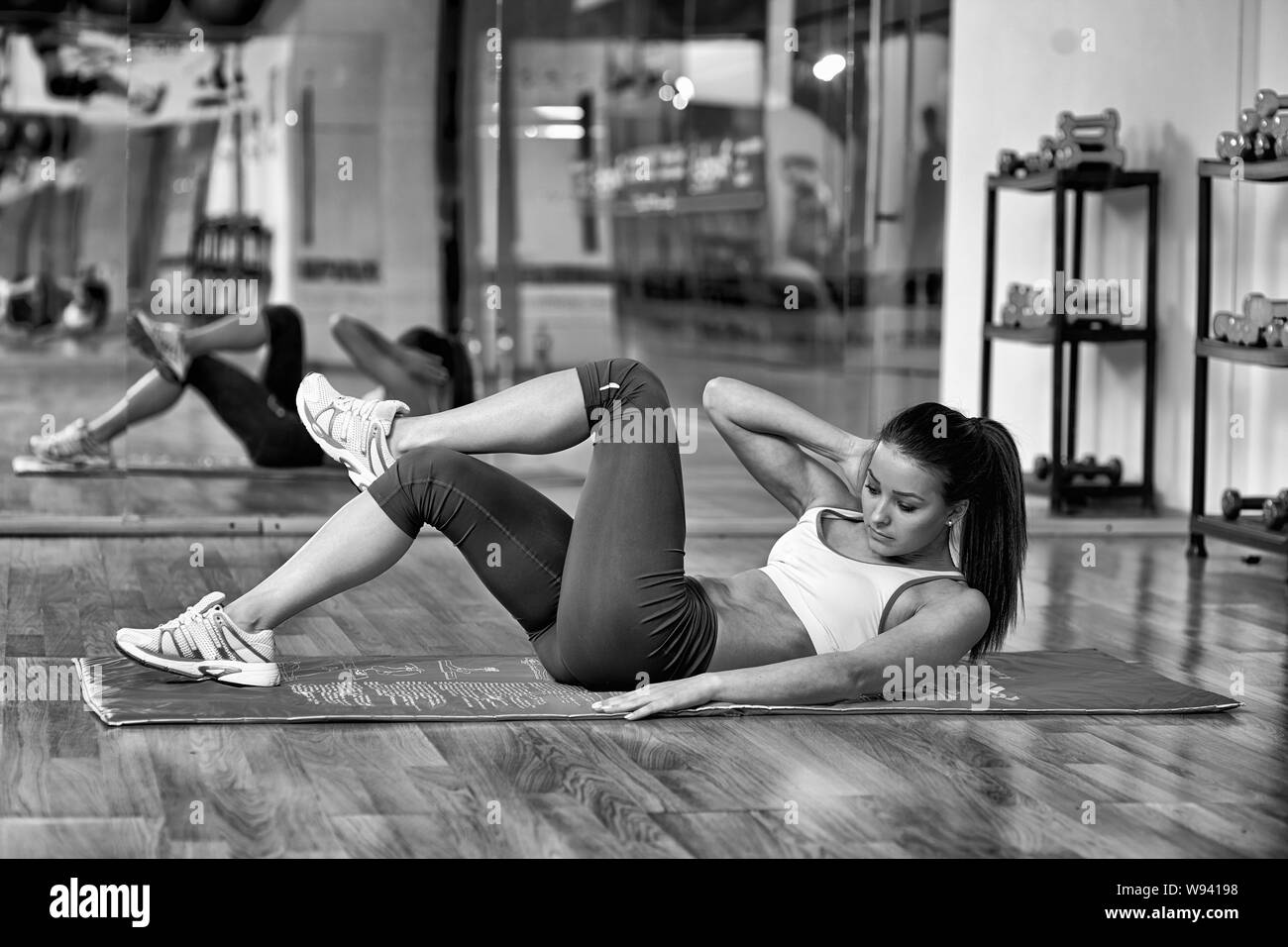 Young woman doing abs workout in a gym on a mat Stock Photo - Alamy