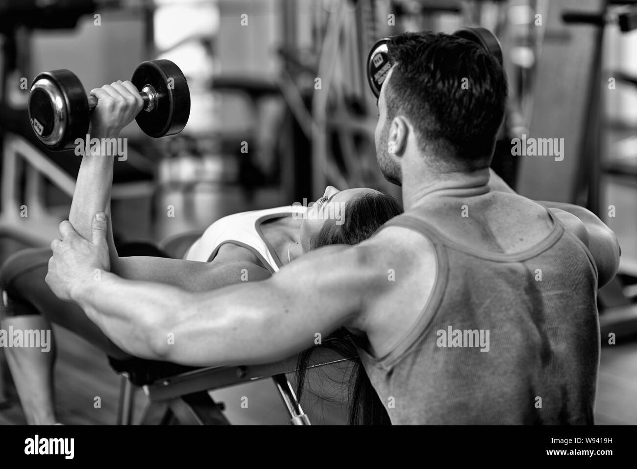 Personal trainer helping woman working with dumbbells Stock Photo