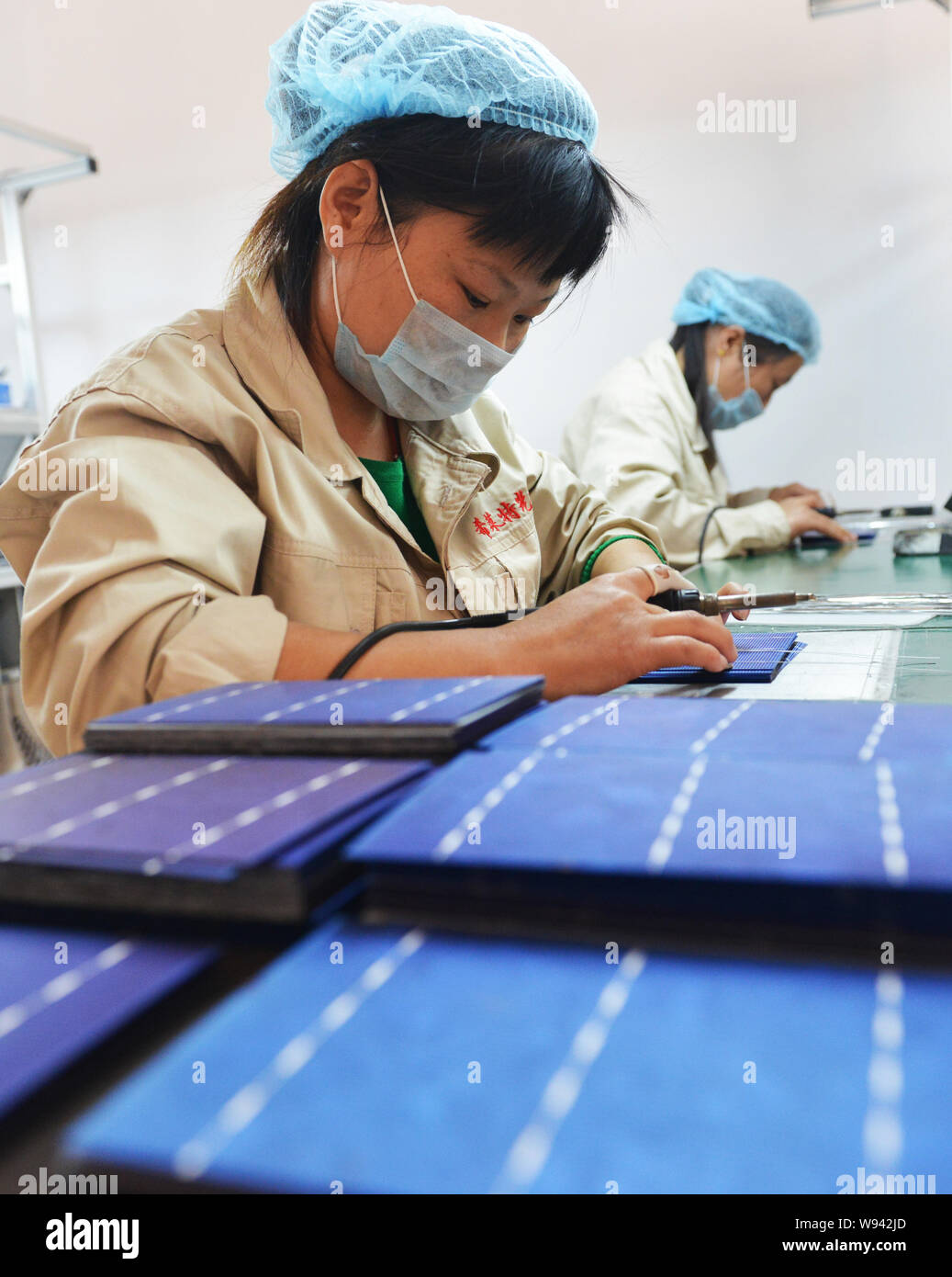 --FILE--Chinese workers weld photovoltaic cells to make solar panels at the factory of Shandong Hilight Solar Co., Ltd. in Zouping county, Binzhou cit Stock Photo