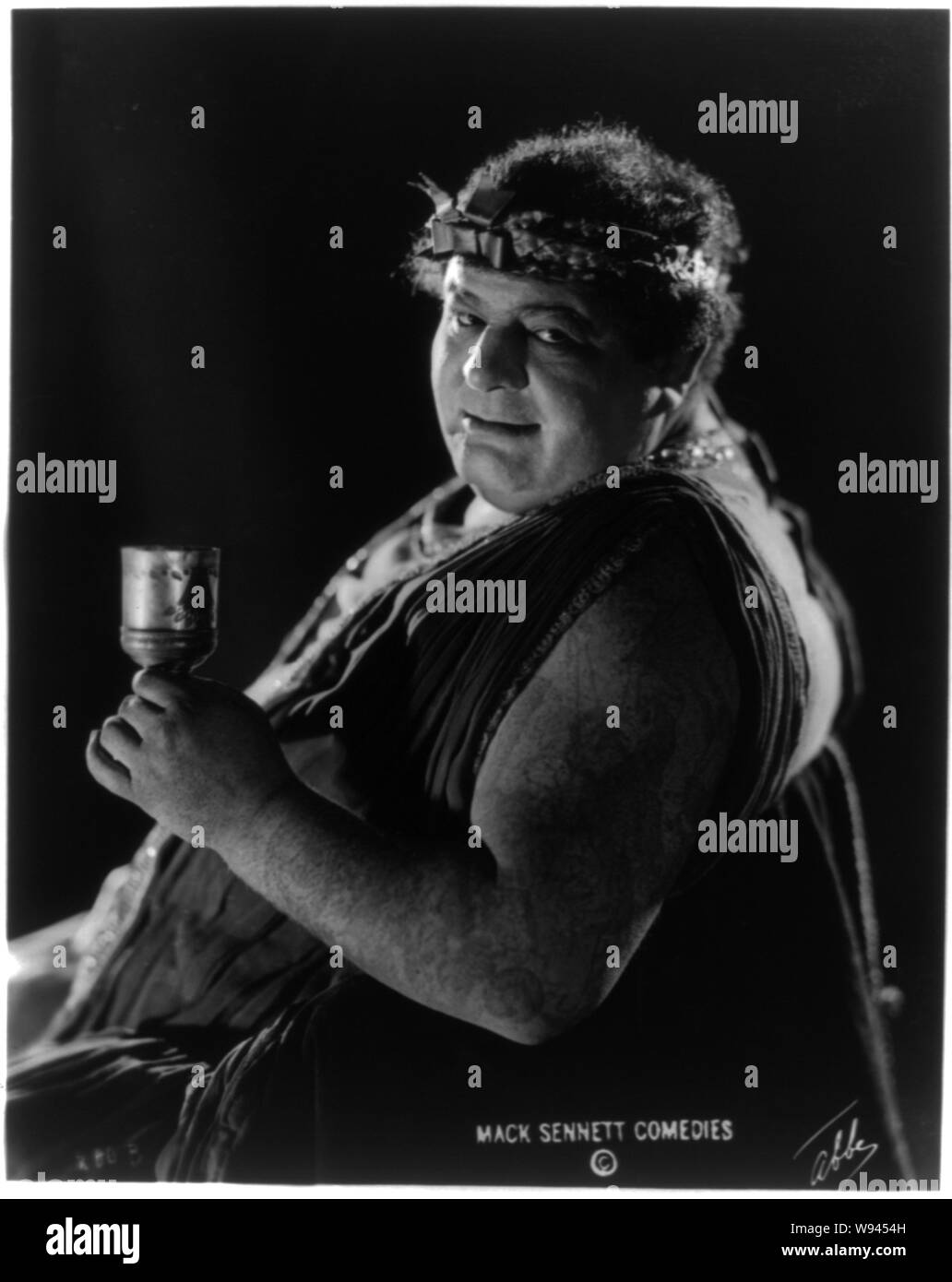 Actor from Mack Sennett comedy film in Roman toga seated holding wine glass / Abbe Stock Photo