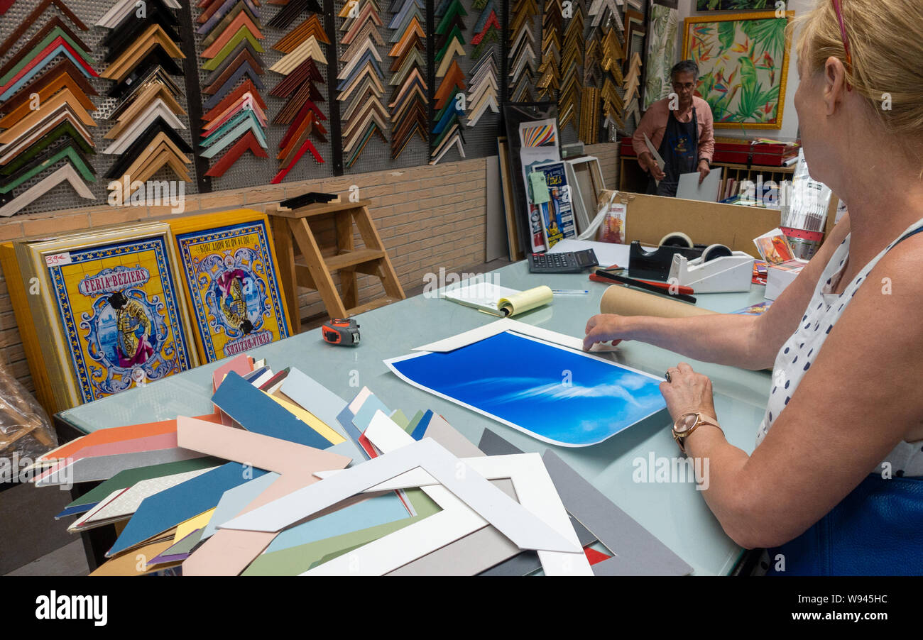Lady choosing a new picture frame in a framing shop with the frame