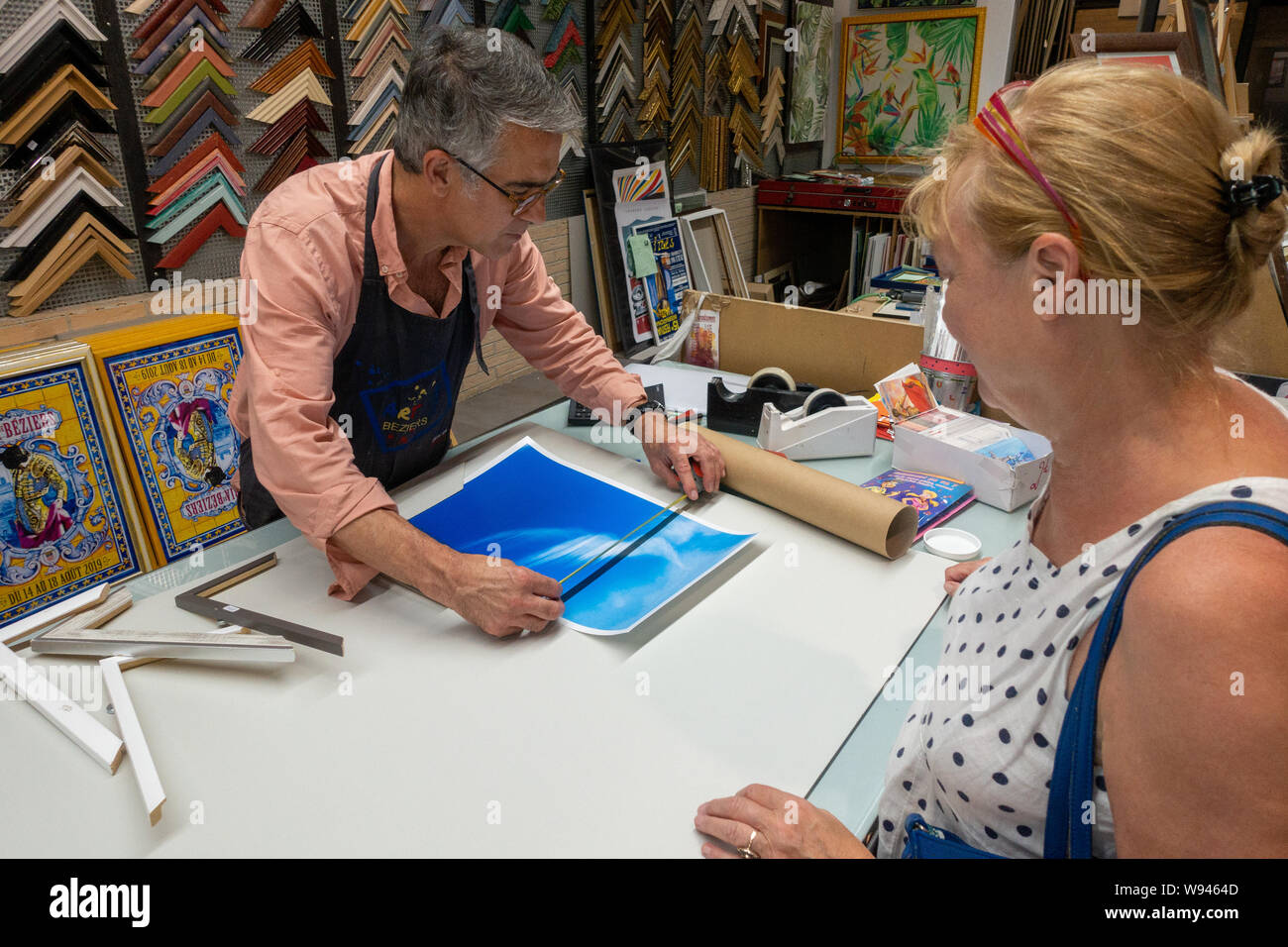 Lady choosing a new picture frame in a framing shop with the frame
