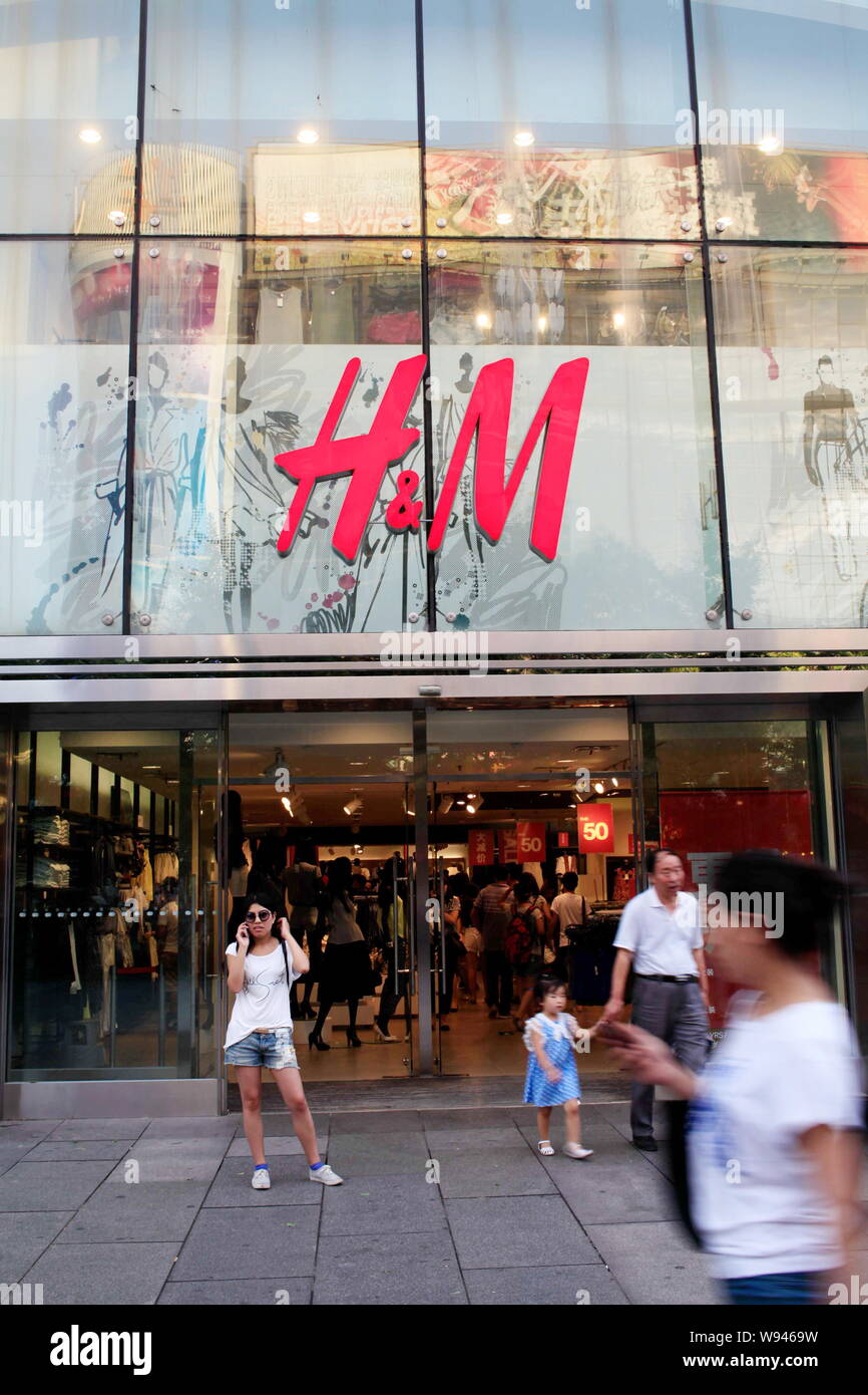 FILE--Pedestrians walk past a fashion store of H&M in Beijing, China, 4  July 2013. Hennes & Mauritz AB is looking to Ethiopia as a new low-cost c  Stock Photo - Alamy