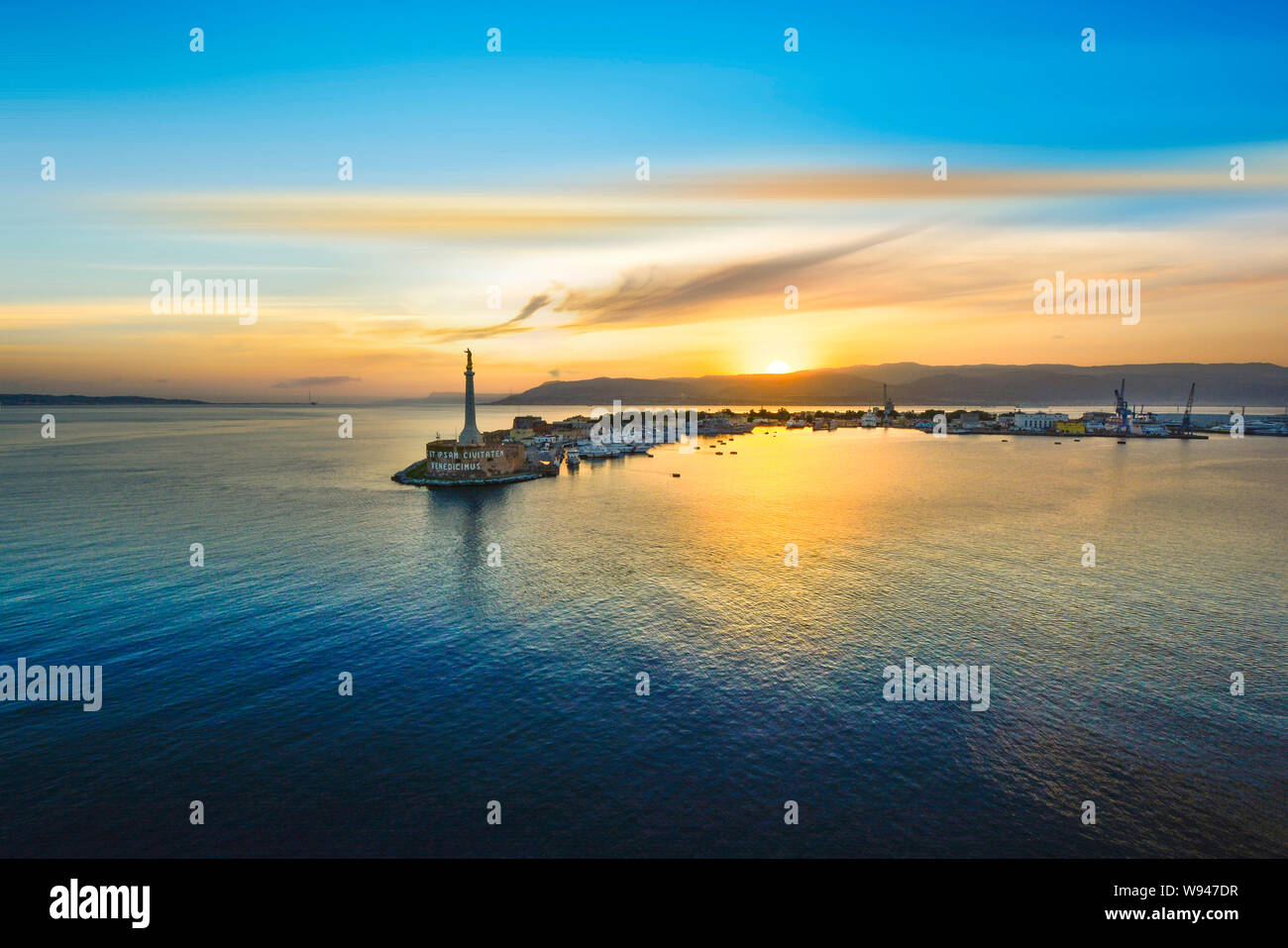 A beautiful sunset behind the golden Madonnina column guarding the port of Messina, Italy, on the Mediterranean island of Sicily. Stock Photo