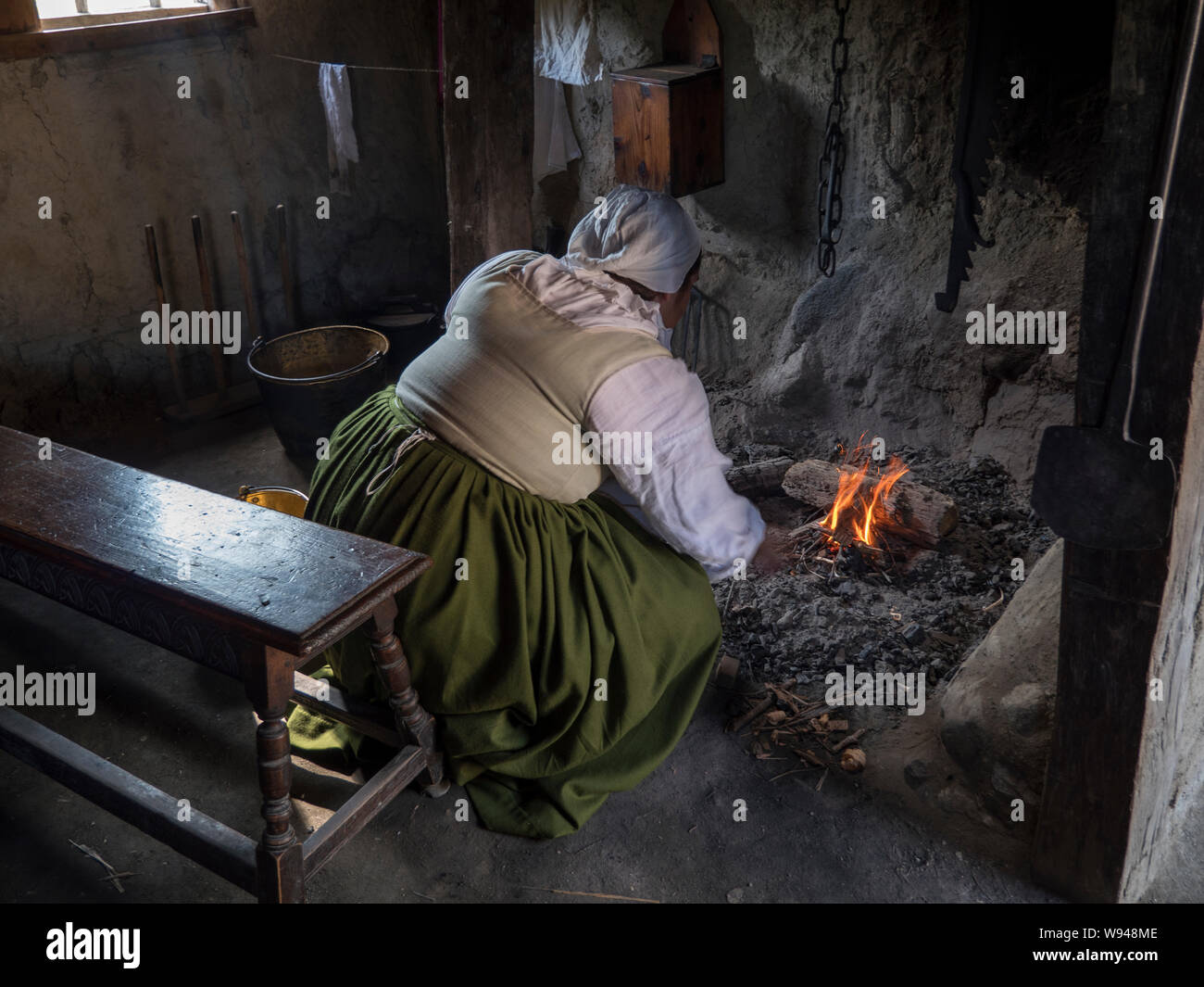 Pilgrim woman tending th fire inside her home Stock Photo