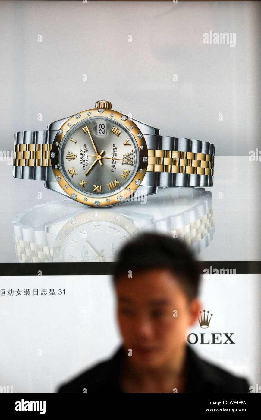 A pedestrian walks past an advertisement for Rolex watches in Shanghai,  China, 28 May 2013. China has signed the framework of a free-trade  agreement Stock Photo - Alamy