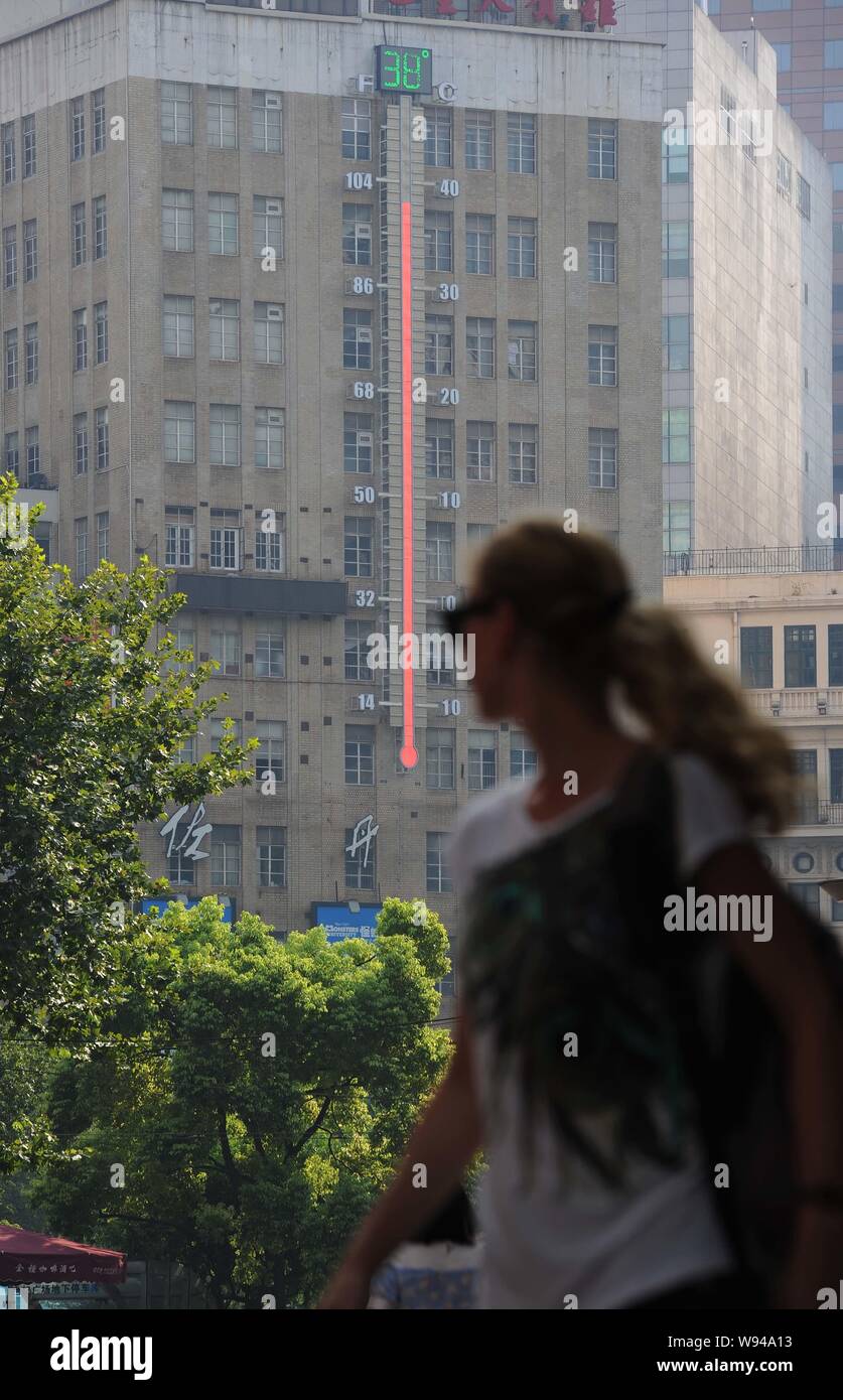 A pedestrian walks past a giant thermometer with the reading reaching 38 degrees Celsius on a scorching day in Shanghai, China, 25 July 2013.   Easter Stock Photo