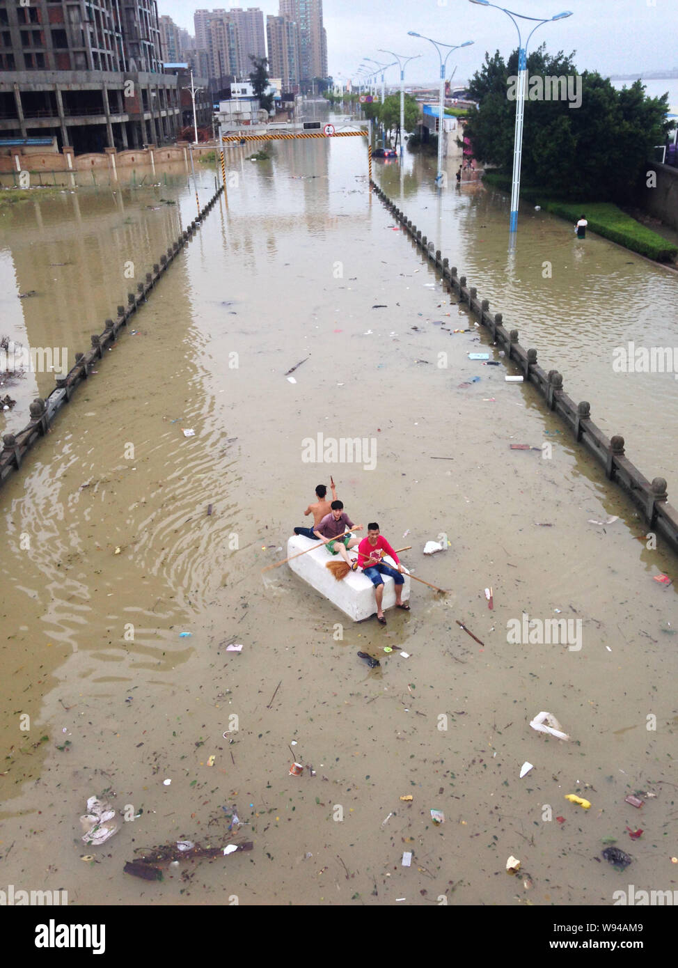 Young Chinese men row a raft on a flooded street after heavy rains caused by Typhoon Fitow in RuiAn city, east Chinas Zhejiang province, 7 October 201 Stock Photo