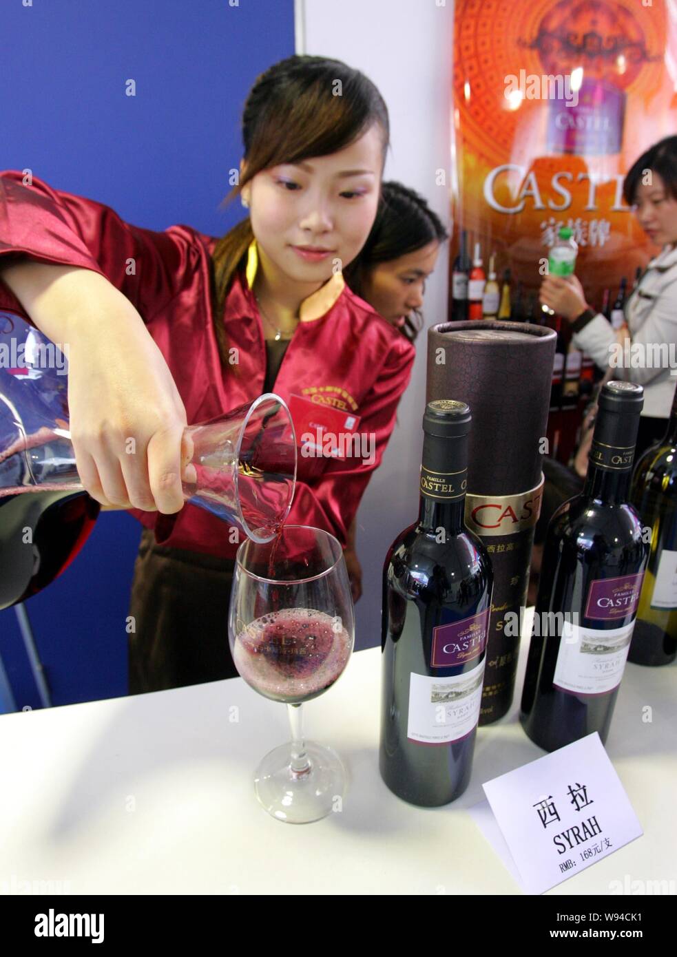 --FILE--A Chinese employee pours wine into a glass at the stand of ...