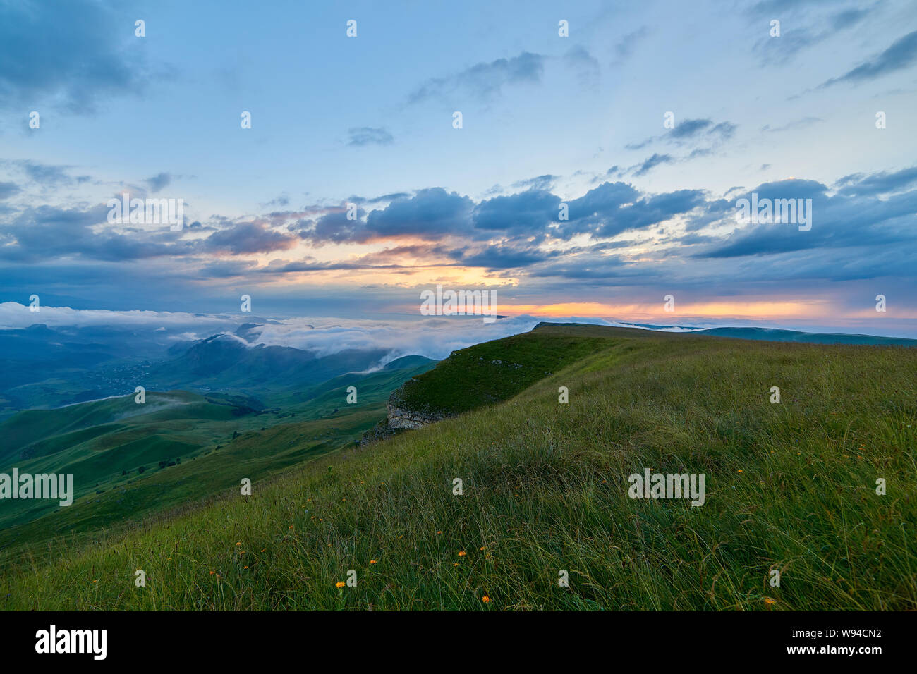 Sunset clouds, blue sky and fog over a mountain valley with a village ...