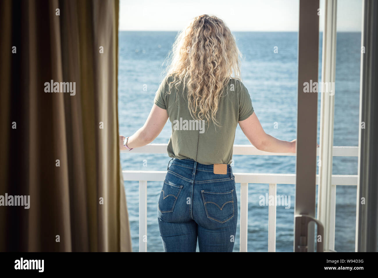 Blond woman looking at the view through the window Stock Photo