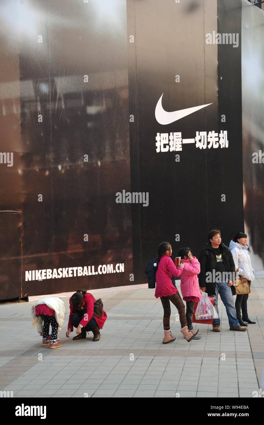 FILE--Shoppers walk past an advertisement of Nike at Wangfujing shopping  area in Beijing, China, 18 November 2011. Nikes flagship store in Beijing  Stock Photo - Alamy