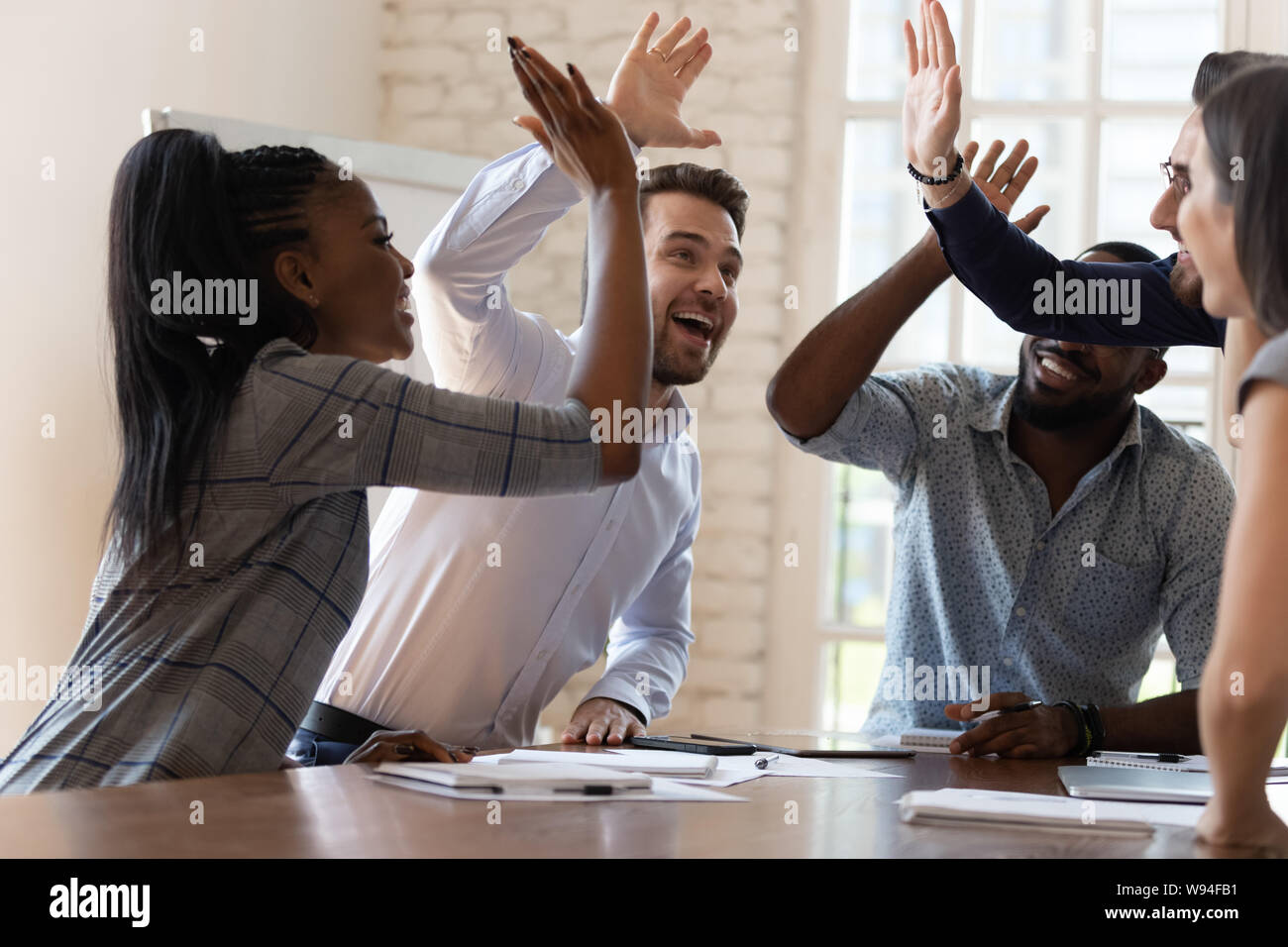 Multiracial euphoric business team people give high five in office ...