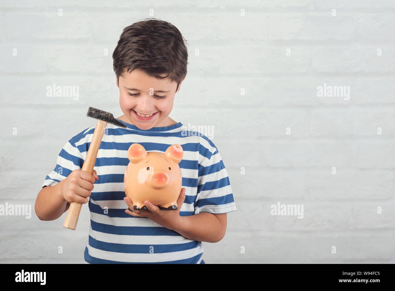 funny child with piggy bank against brick background Stock Photo