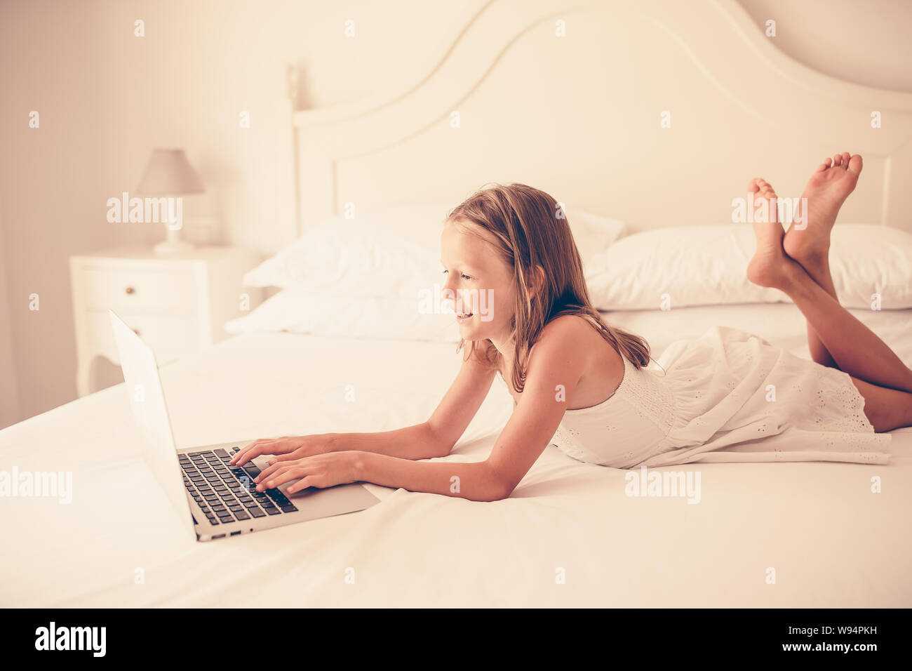 Download this stock image: Cute little girl doing homework on laptop - W94P...