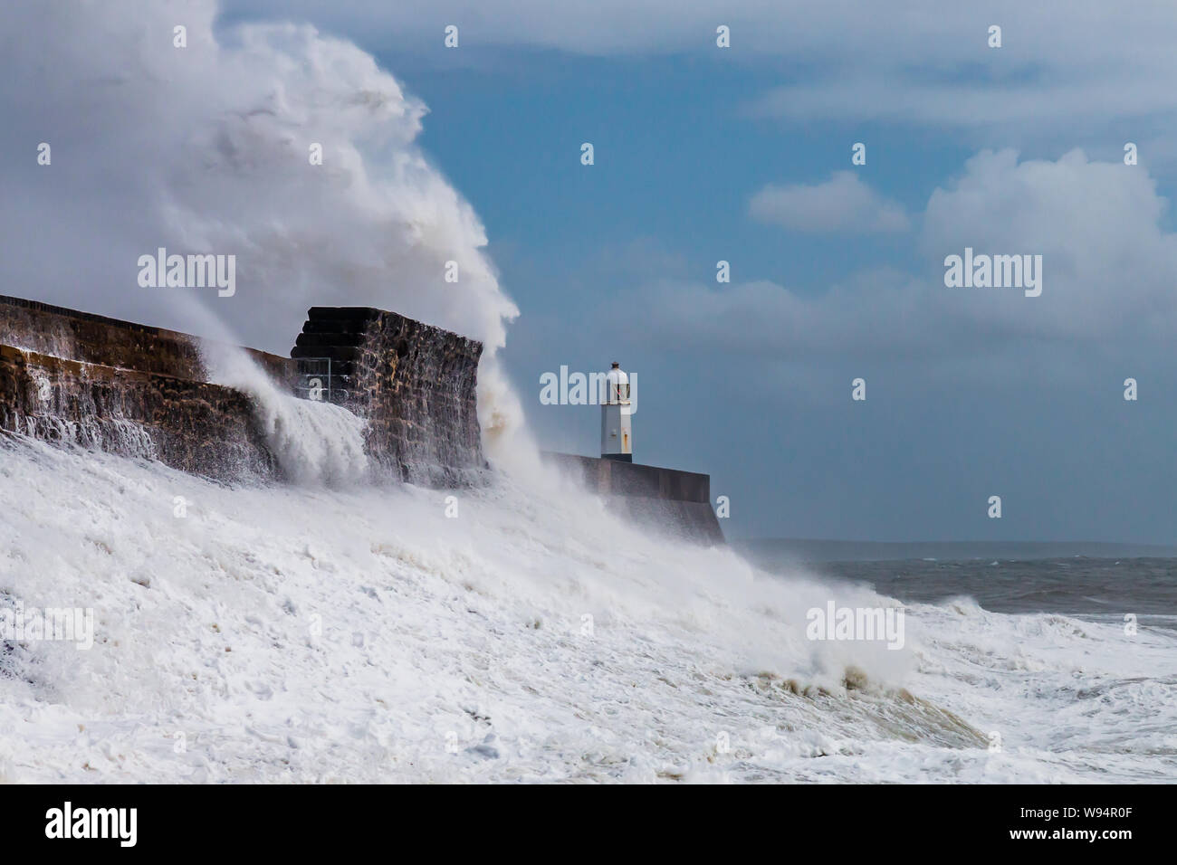 Huge ocean waves crashing into a sea wall and lighthouse (Porthcawl, South Wales, UK) Stock Photo