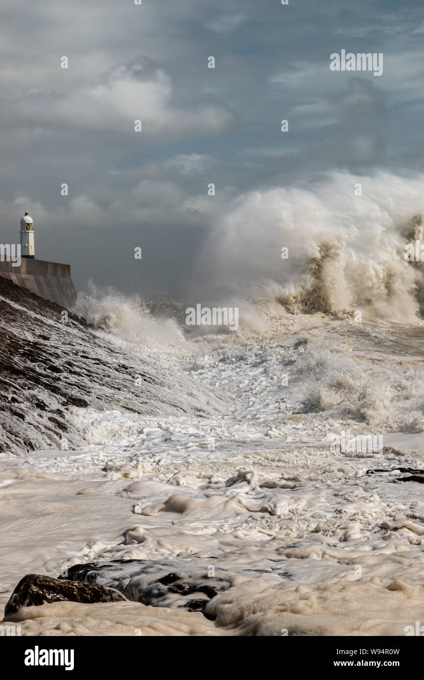 Huge breaking waves next to a lighthouse on a stormy day (Porthcawl, Wales, UK) Stock Photo