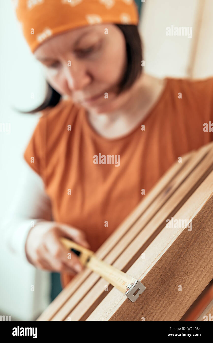 Female carpenter tape measuring wooden crate in her small business woodwork workshop Stock Photo