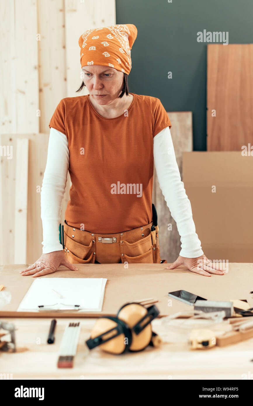 Self employed female carpenter planning DIY project in her small business woodwork workshop Stock Photo