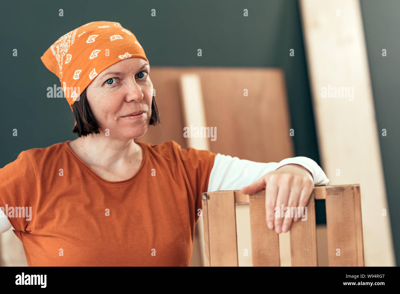 Proud female carpenter posing with finished wooden crate in her small business woodwork workshop Stock Photo