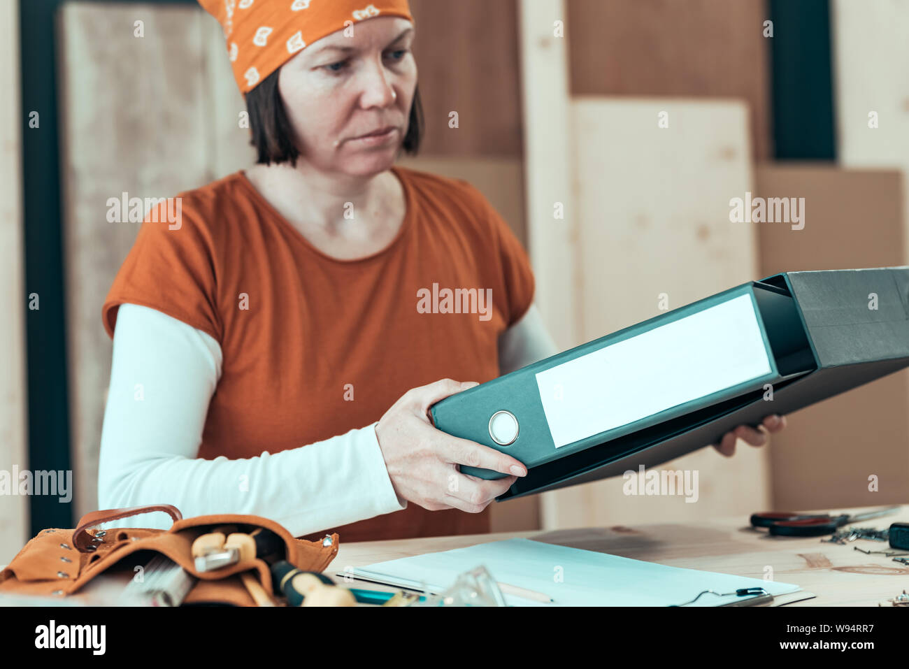 Self employed female carpenter with document ring binder in small business woodwork workshop, selective focus Stock Photo