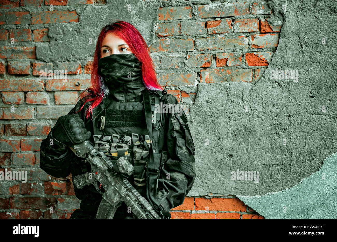 Redhair woman in military uniform with machine gun on bricks wall background Stock Photo Alamy