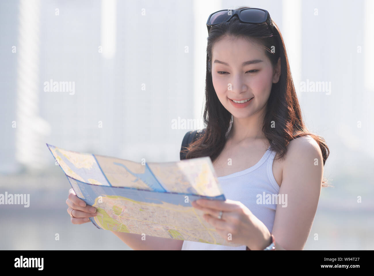 Beautiful asian solo tourist woman  looking at the map searching for tourists sightseeing spot. Vacation travel in summer. Stock Photo