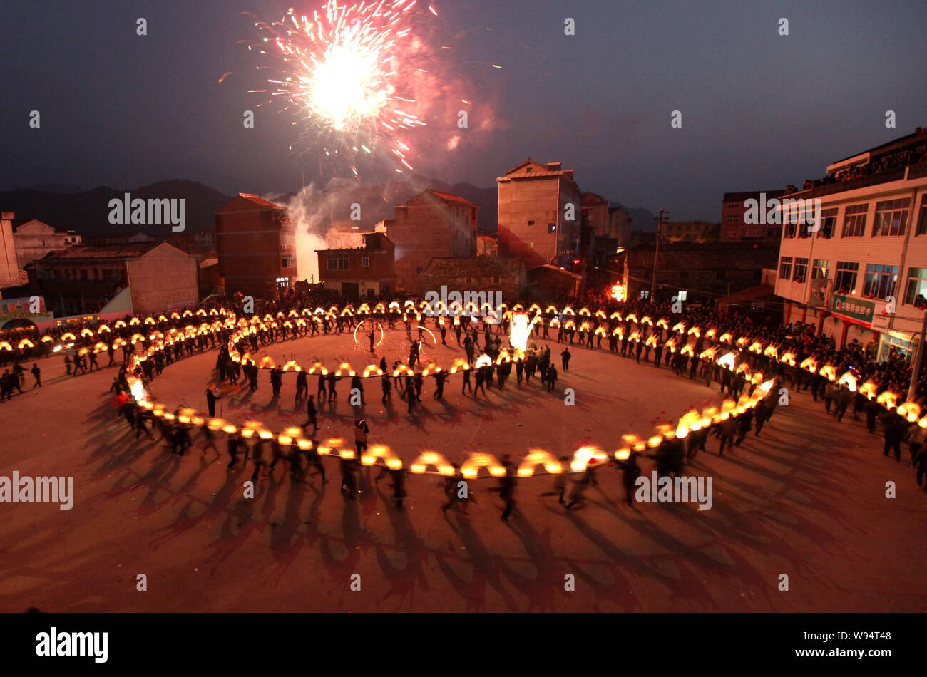 Local Chinese villagers perform a dragon dance with a long bamboo dragon decorated with lit lanterns to celebrate the forthcoming Lantern Festival on Stock Photo