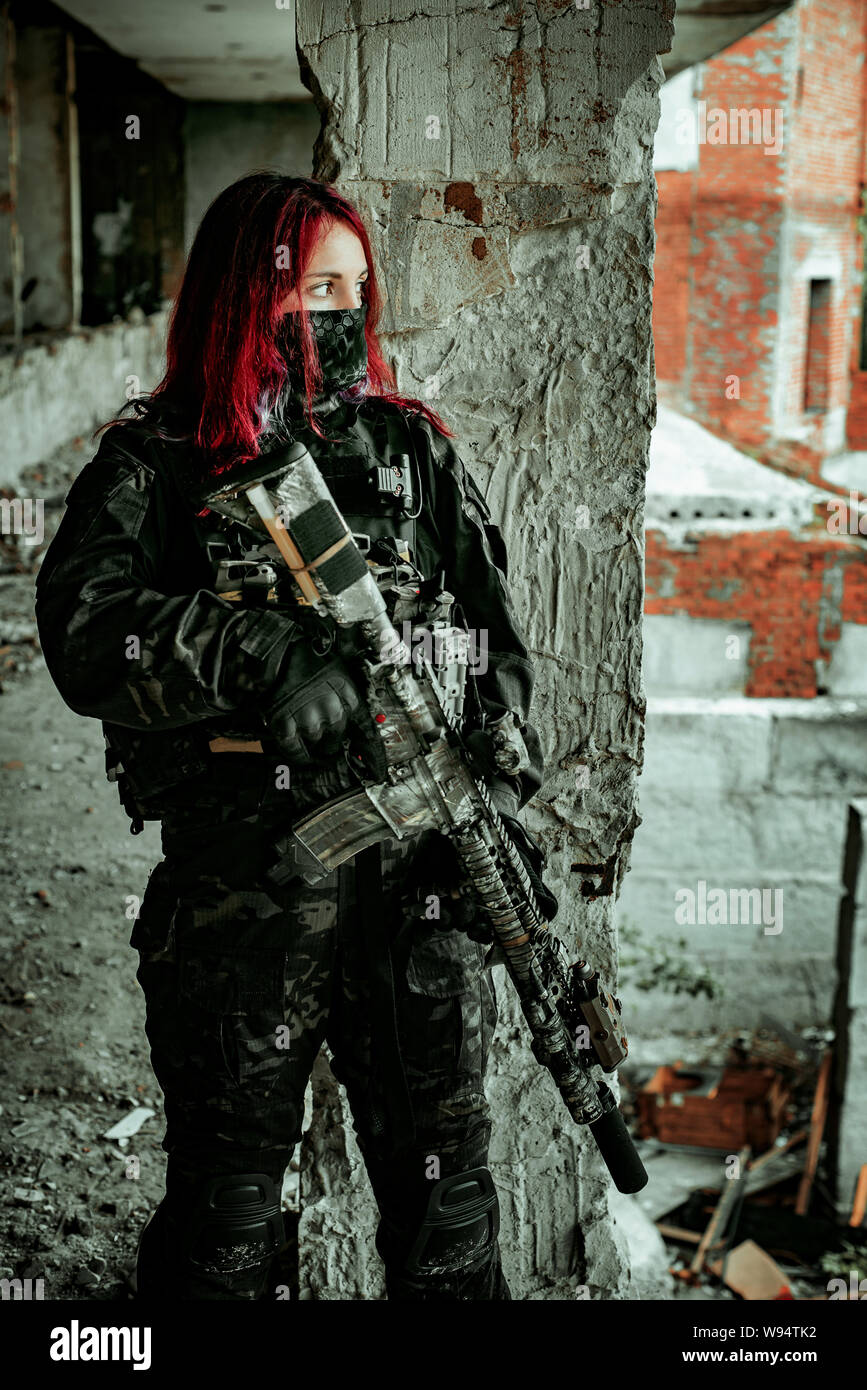 Redhair woman in military uniform with machine gun inside ruine Stock