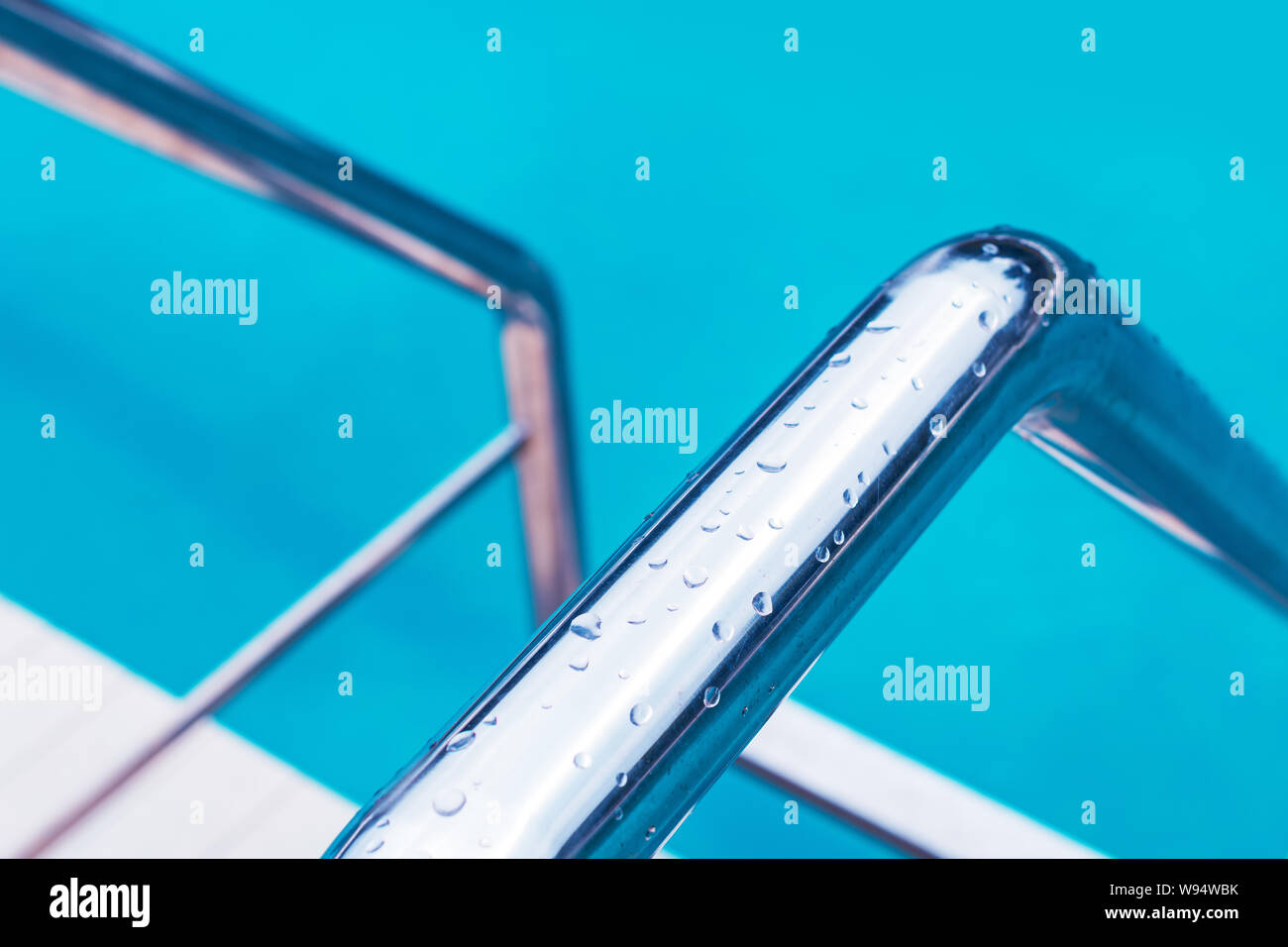 Outdoor swimming pool water and aluminum ladder with no people, summer vacation holiday abstract background Stock Photo