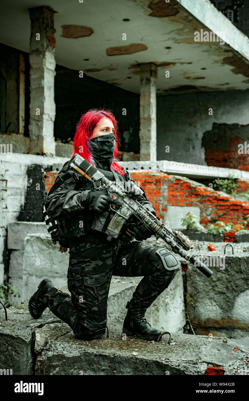 Redhair woman in military uniform with machine gun inside ruine Stock