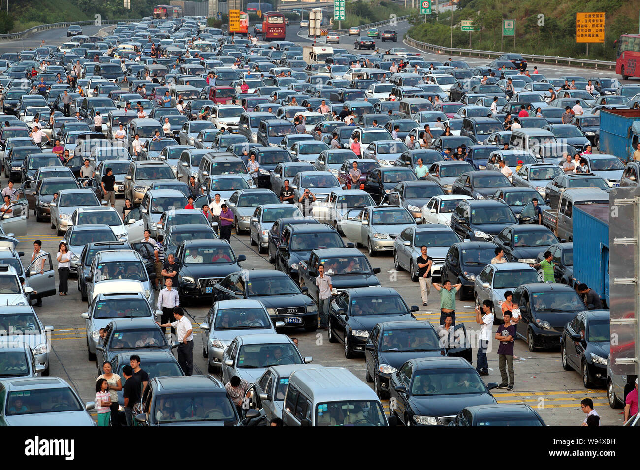 Chinese holidaymakers rest next to their cars as they are waiting in a long queue in a traffic jam on an expressway during the Mid-Autumn Festival and Stock Photo