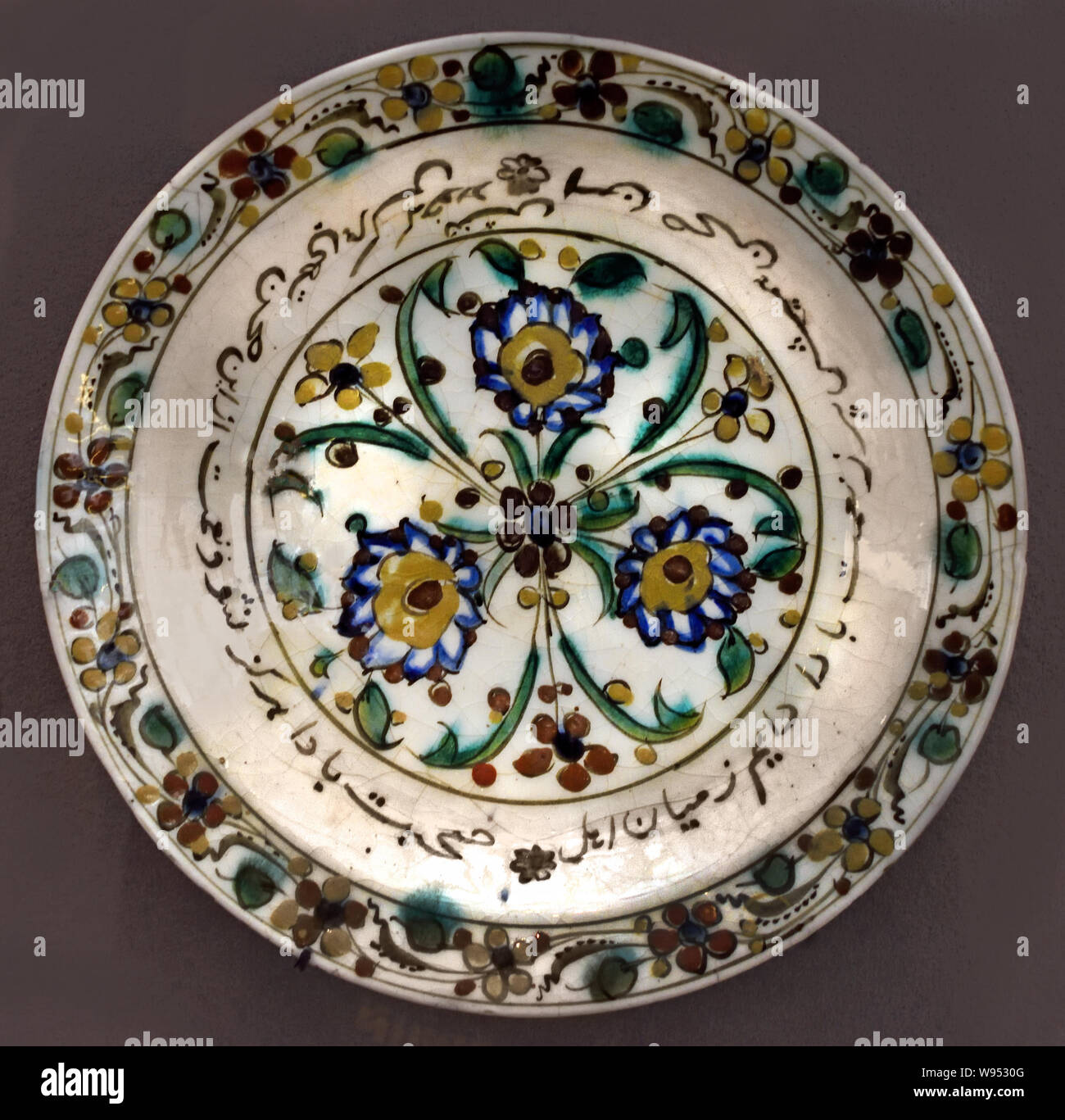 The inscription in Persian says: 'May this dish be always full, always surrounded by friends, that they never miss anything and that they feast well.  dish late 16th - early 17th century Iran, Ceramic, painted underglaze decoration. Stock Photo