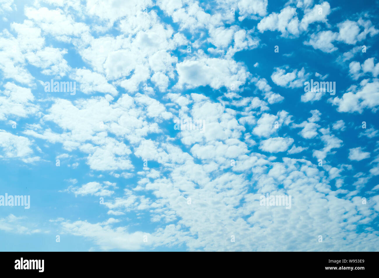 Blue dramatic sky background - white dramatic colorful clouds lit by sunlight. Vast sky landscape panoramic scene. Sunny blue sky scene Stock Photo