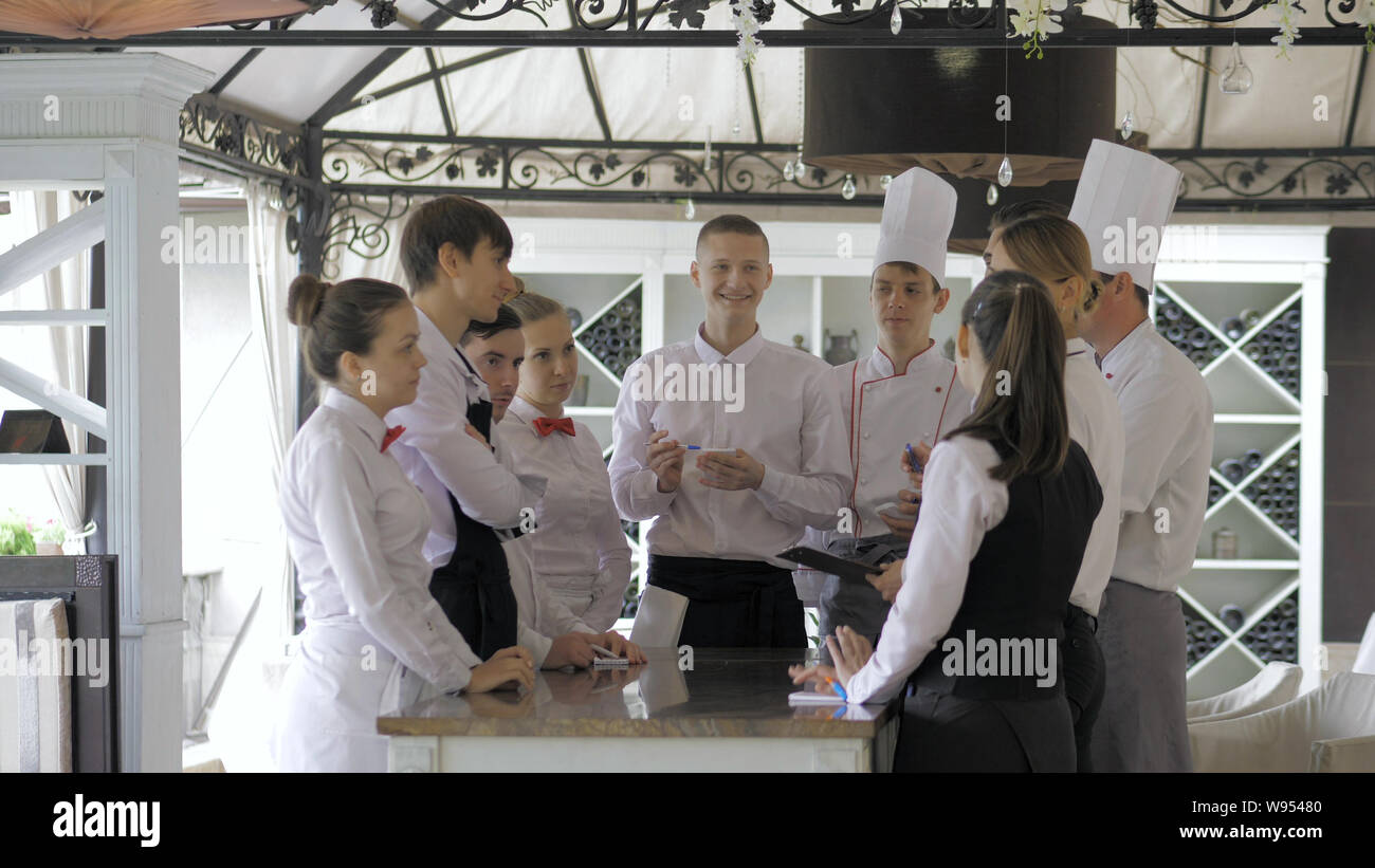 Restaurant manager and his staff in terrace. Interacting to head chef ...