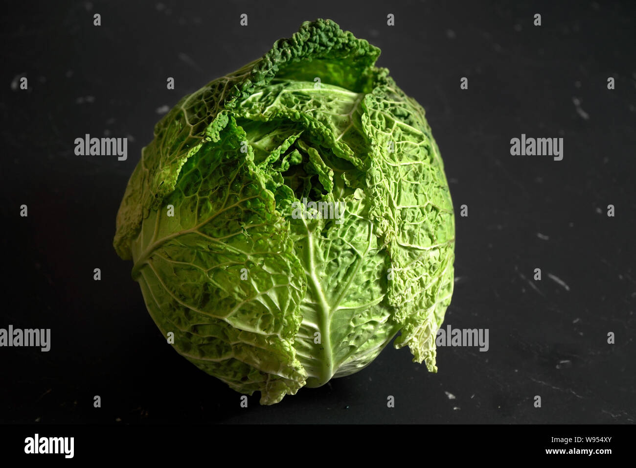 Closeup of savoy cole cabbage on black desk with marble effect. Stock Photo