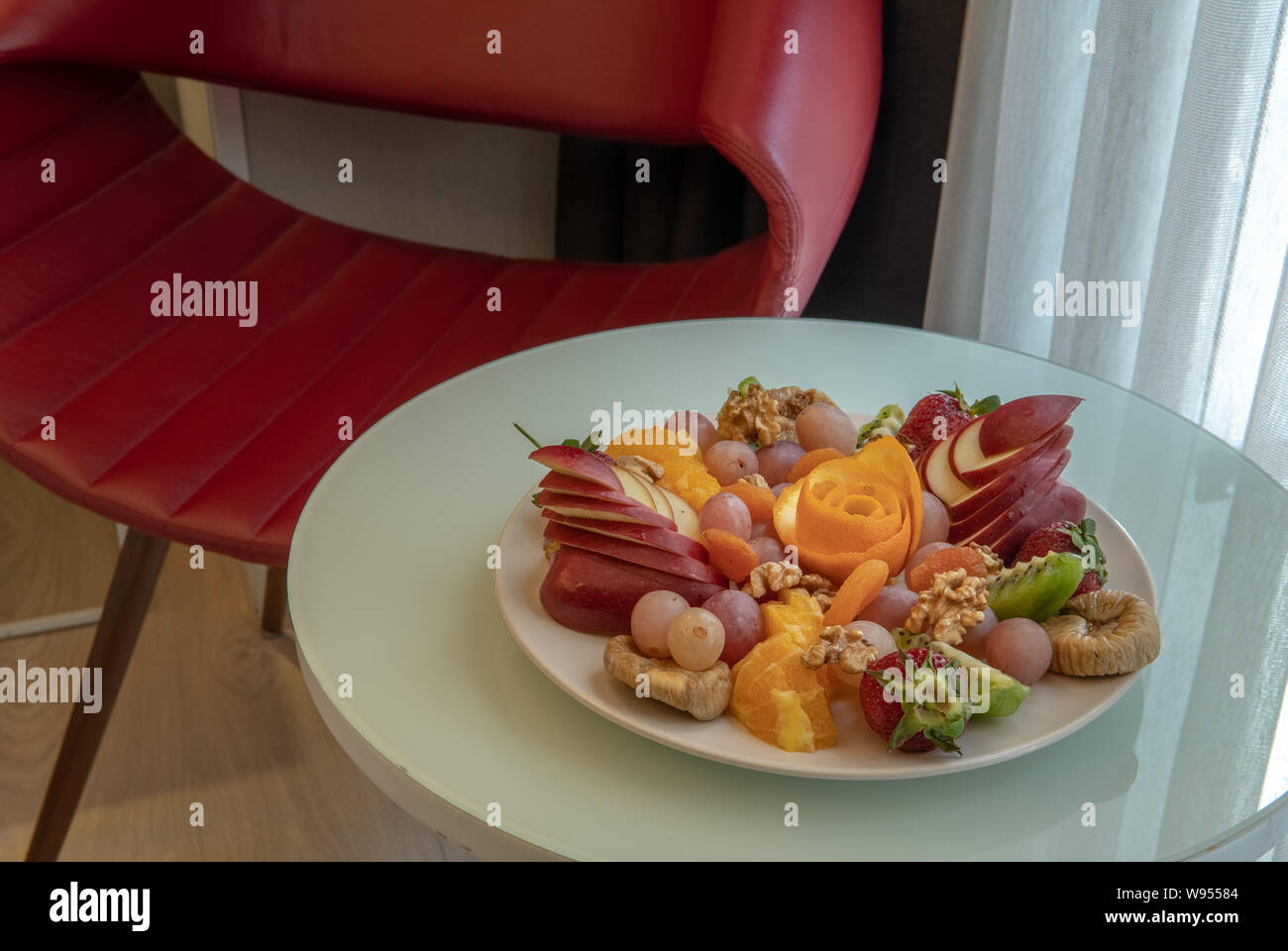 Fruit platter in hotel room with red chair in background Stock Photo