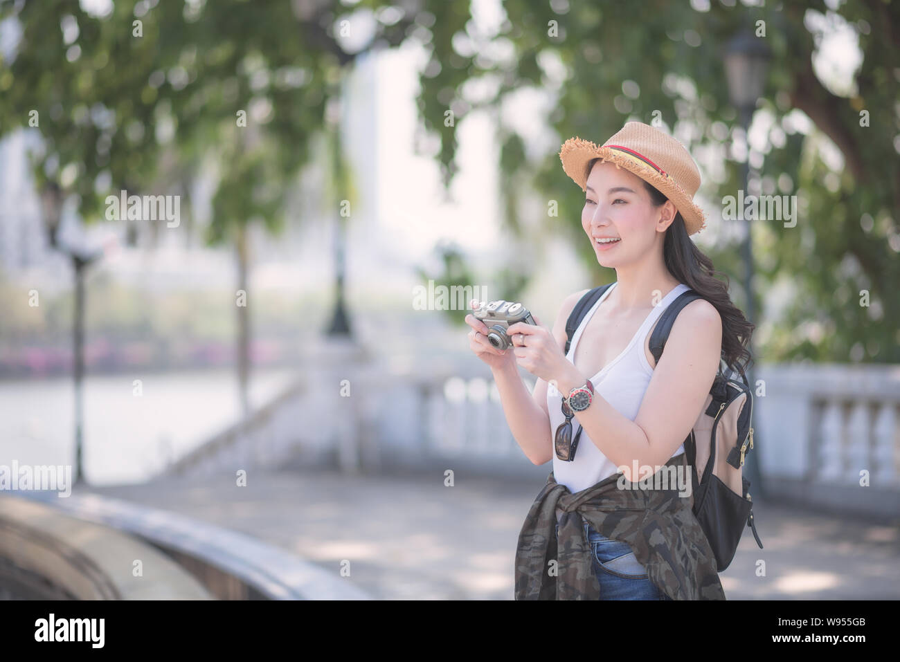 Beautiful asian solo tourist woman enjoy taking photo by retro camera at tourist sightseeing spot. Vacation travel in summer. Stock Photo