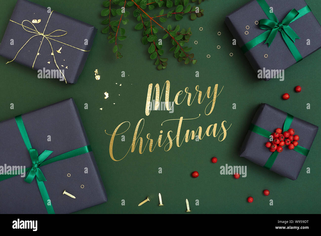 Merry Christmas text and Christmas gifts on green background, presents flat lay with Christmas greetings Stock Photo