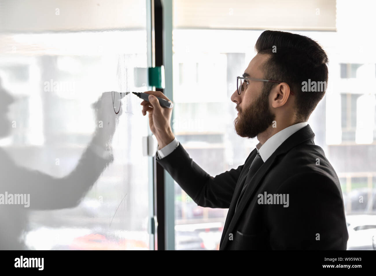 Millennial businessman wearing glasses drawing on flip chart close up Stock Photo