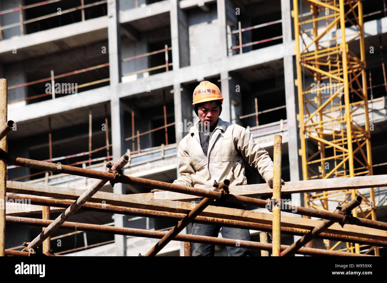 A Chinese worker carries building materials at the construction site of
