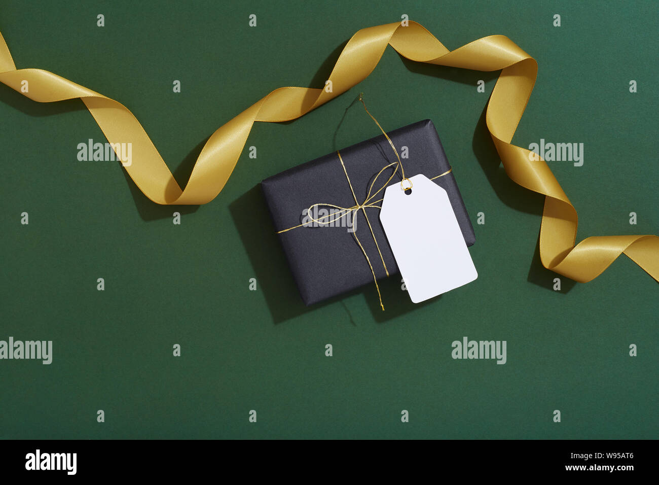 Black Christmas gift box and price tag, gift tag on green background Stock Photo