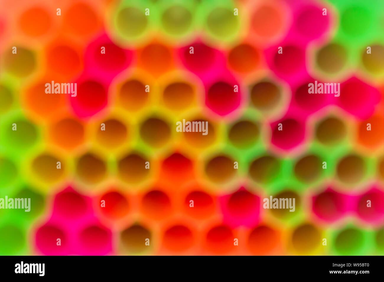 Blurred background of multicolored plastic cocktail tubes. Backgdrop of bright yellow, red, pink and green neon colors. Abstract colorful background. Stock Photo