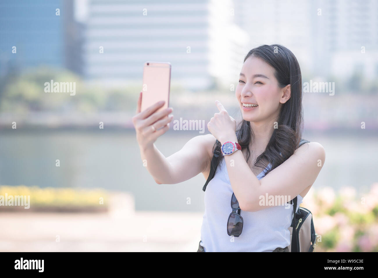 Beautiful asian woman enjoy using video call technology on a smartphone in urban city downtown. Vacation travel in summer. Stock Photo