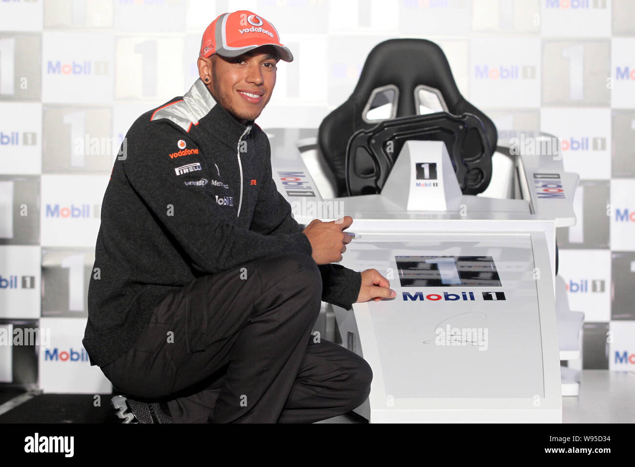 British F1 driver Lewis Hamilton of the McLaren-Mercedes team poses with a F1 racing car simulator during a promotional event by Mobile in Shanghai, C Stock Photo