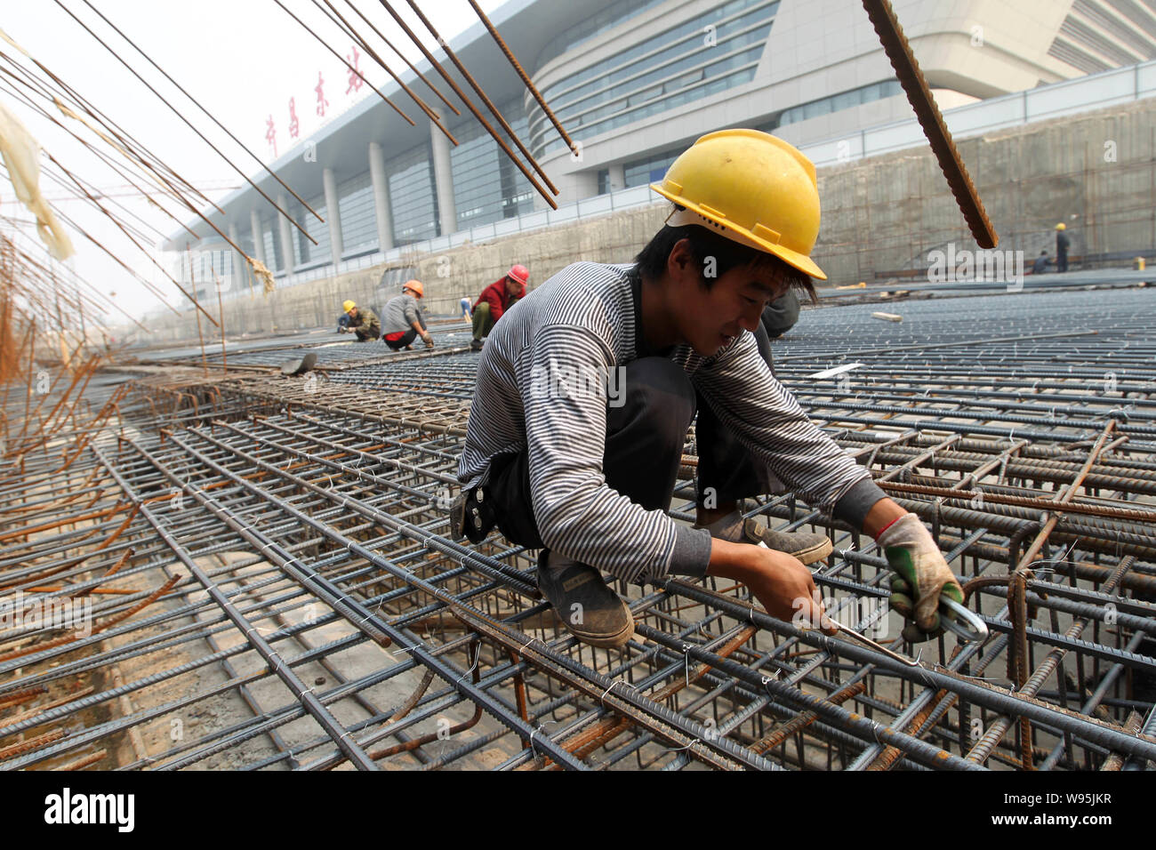 Chinese migrant workers tightern reinforcing steel rods at a ...