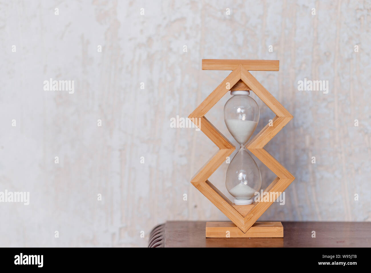 Close up of hourglass clock on a wooden floor with copy space. Hourglass time passing concept for business deadline, urgency and running out of time Stock Photo